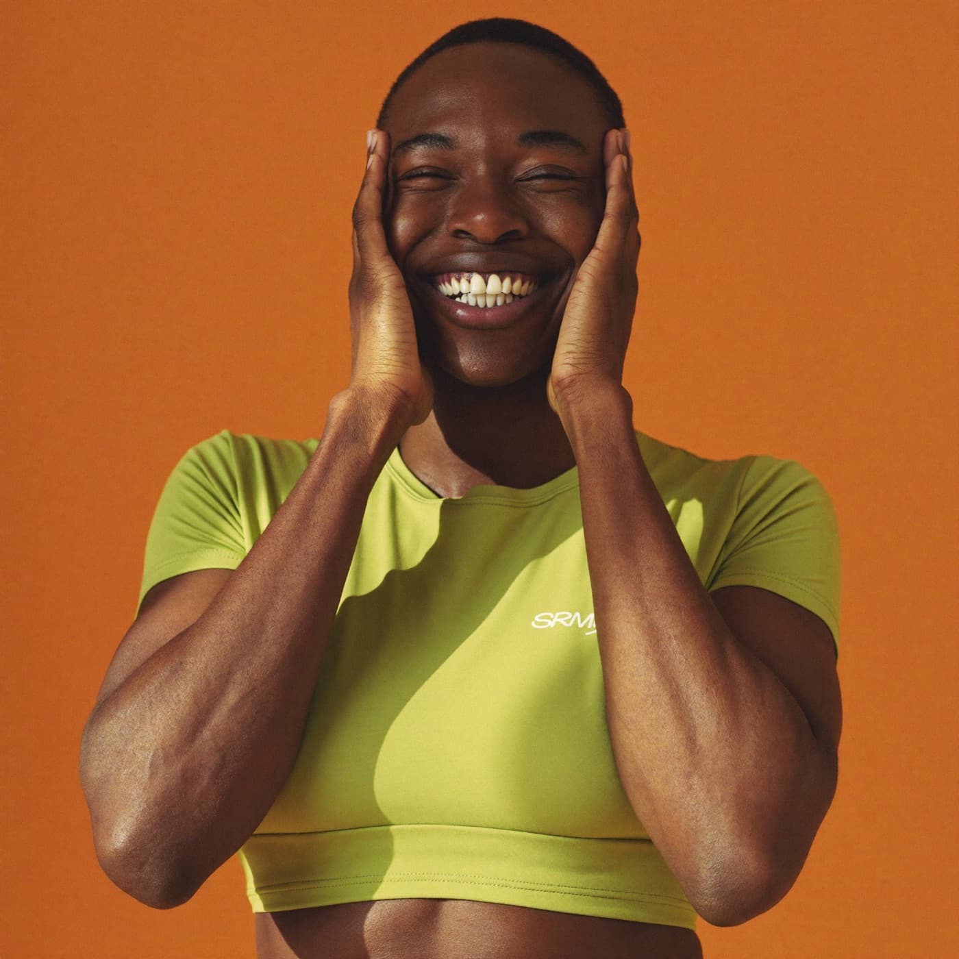 a fitness creator grinning against an orange backdrop
