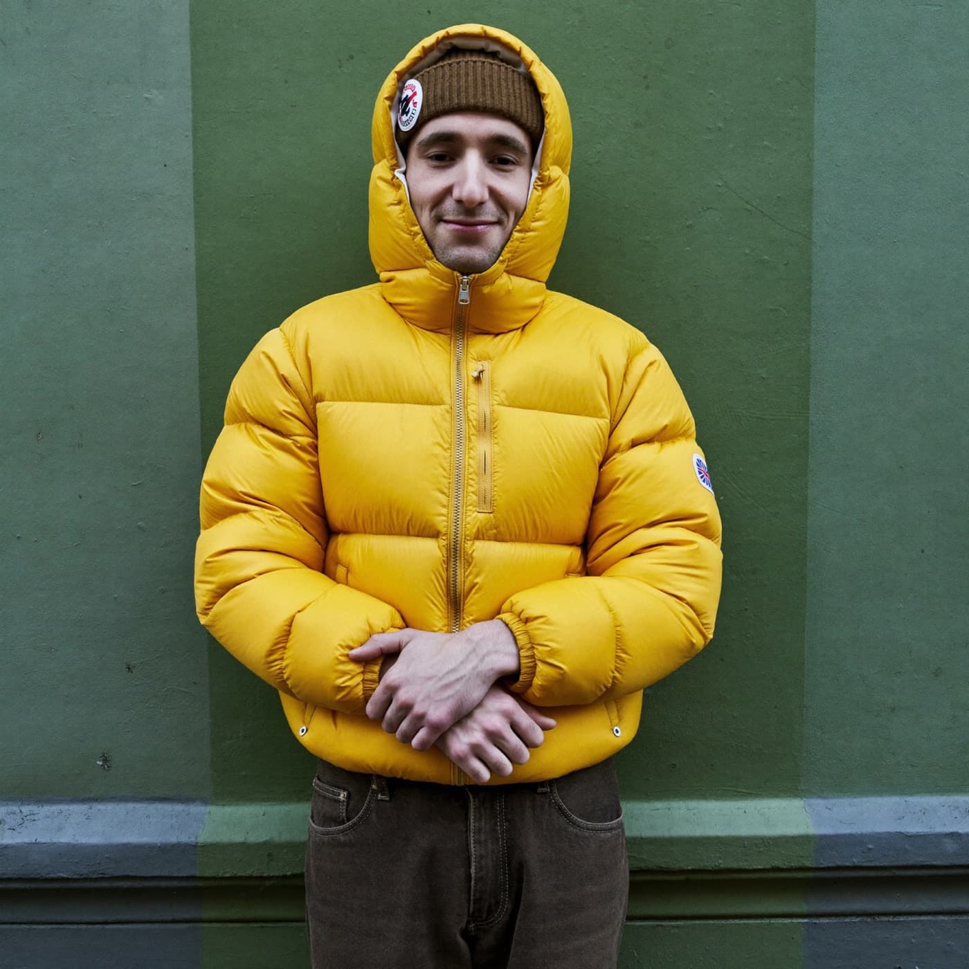 a streetwear creator in a yellow puffer against a teal wall